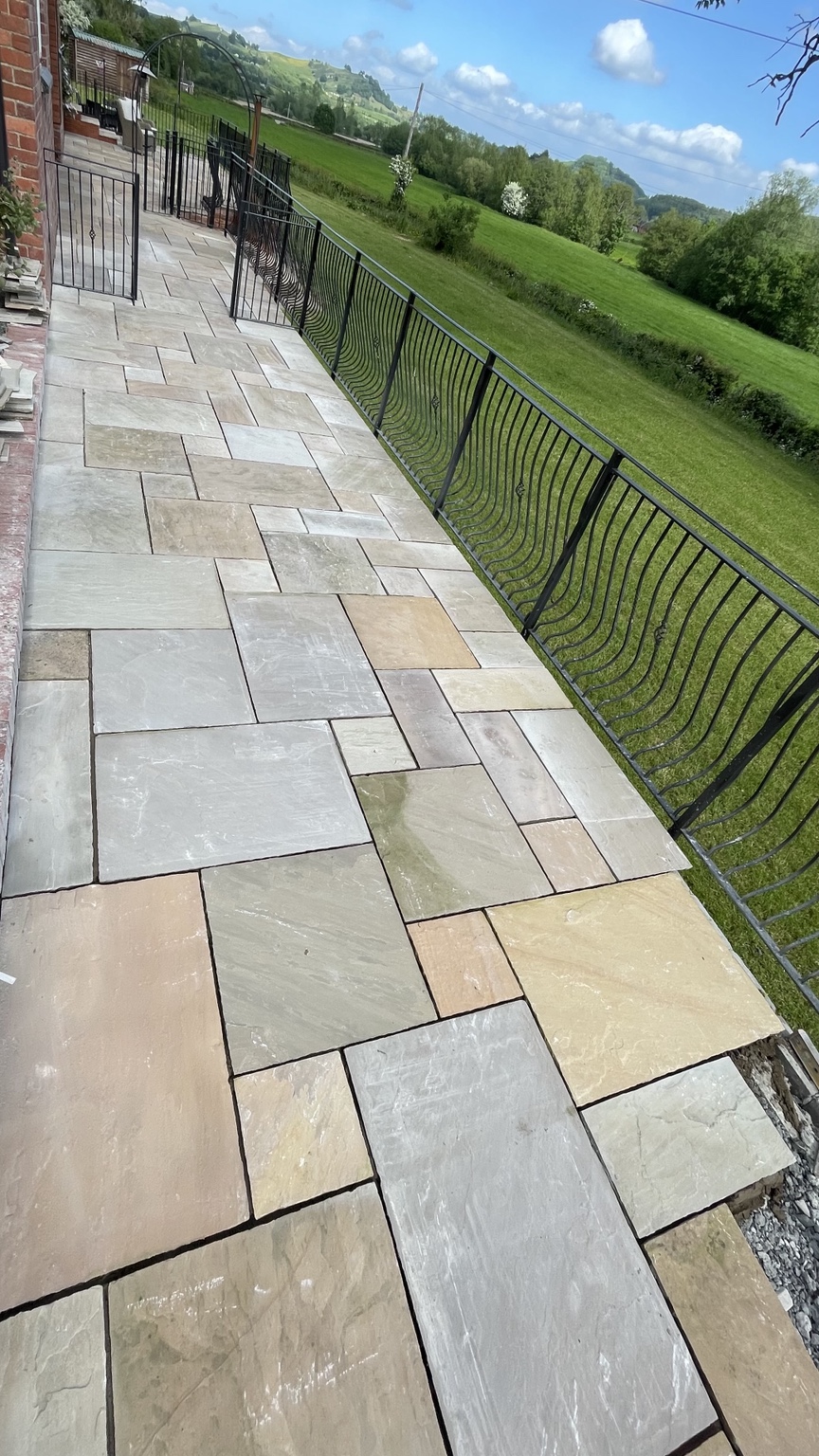 Indian sandstone patio with railings overlooking the garden